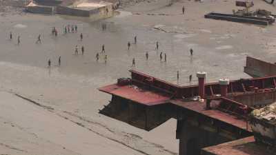 Carcasses of dismantled boats on the seafront, workers at work